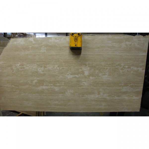 A white travertine cross cut slab in a warehouse.
