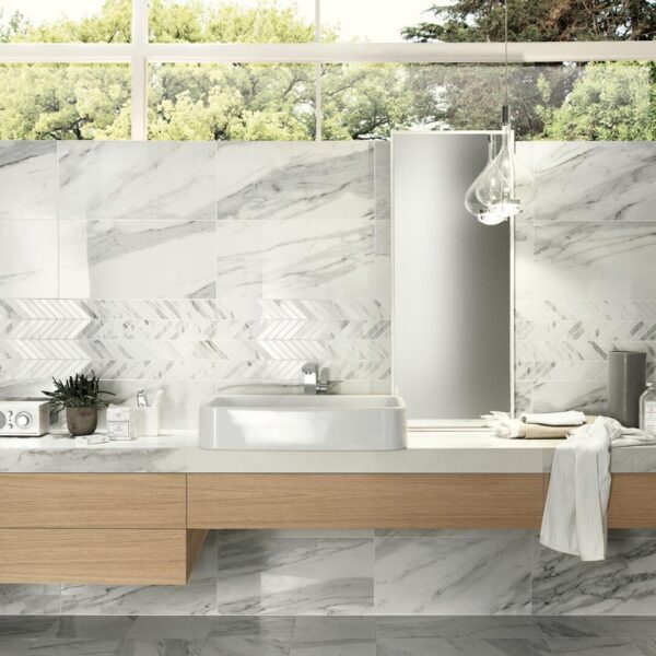 A bathroom with white marble tiles and wooden cabinets.