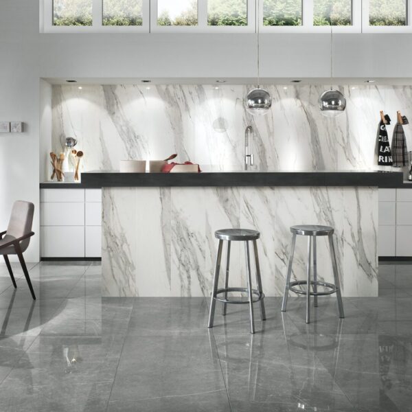 A modern kitchen with marble counter tops and stools.