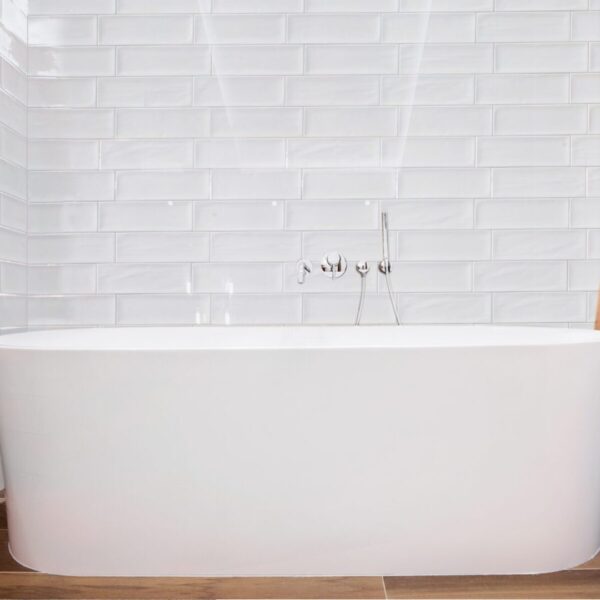 A white bathtub sitting in front of a brick wall.