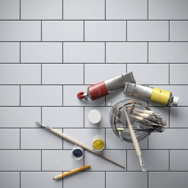 A white tiled wall with some paint and brushes